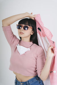 Young woman wearing sunglasses against white background