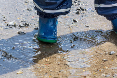 Low section of man standing on wet shore