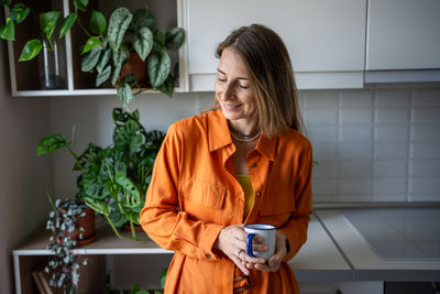 Portrait of young woman standing against wall