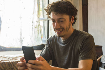 Young man looks at his cell phone smiling