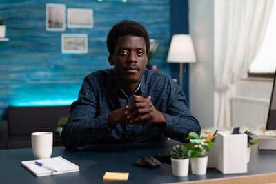 Young man looking down while sitting on table