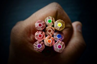 Cropped hand of person holding colored pencils