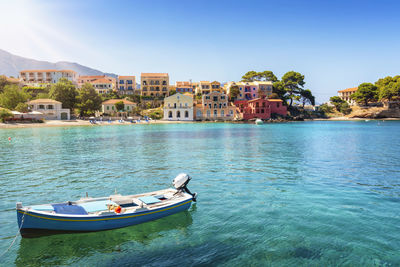 Boats in sea by buildings against sky