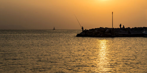 Silhouette sailboats in sea against sky during sunset