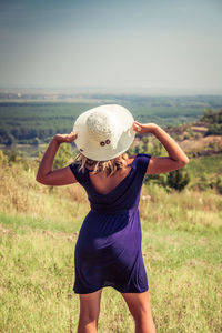Rear view of woman wearing hat standing on field