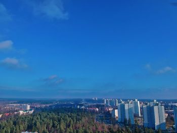 High angle view of buildings in city against blue sky