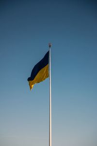 Low angle view of flag against clear blue sky