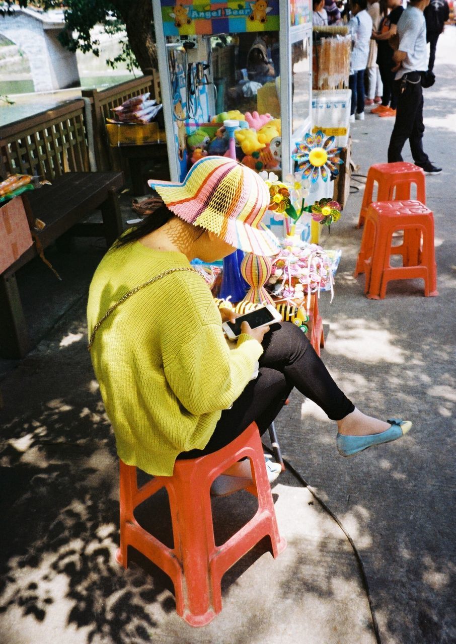 street, rear view, men, domestic animals, text, sitting, incidental people, market, day, outdoors, person, pets, focus on foreground, animal themes, lifestyles, retail, communication, dog