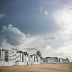 People standing by buildings against sky in city