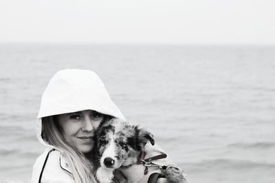 Portrait of young woman holding dog at beach