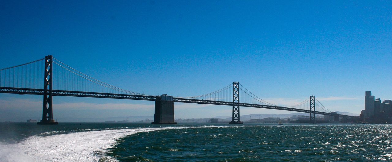 water, connection, built structure, bridge, architecture, bridge - man made structure, blue, sky, engineering, clear sky, suspension bridge, transportation, nature, tourism, copy space, travel destinations, sea, travel, outdoors, bay, long