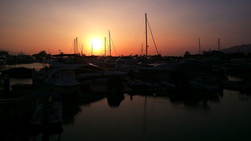 Sailboats moored at harbor during sunset