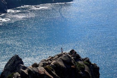 High angle view of man standing on rock against sea