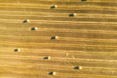 Aerial drone view of mown field with scattered hay bale rolls