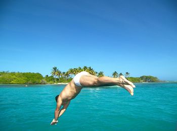 Man swimming in sea against clear blue sky