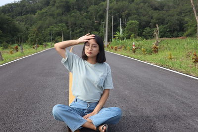 Portrait of young woman sitting on road