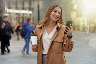 Smartphone using. take away coffee. smart watch. blurred people background.