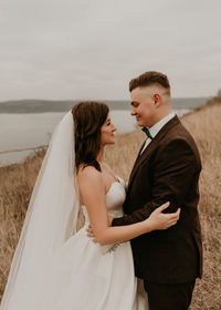 Portrait of smiling couple standing at beach