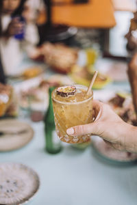 Hand of man holding cocktail glass garnished with passion fruit slice at restaurant