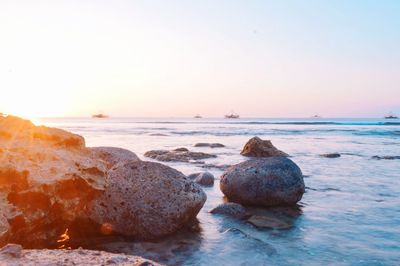 Rocks on beach against sky during sunset