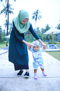 Rear view of mother and daughter standing outdoors