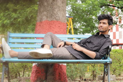 Young man sitting on bench in park