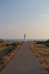 Road leading towards lighthouse against sky during sunset