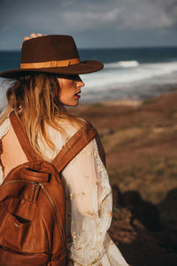 Rear view of woman carrying backpack while standing at beach