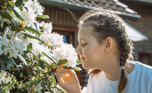 Side view of young woman blowing flowers