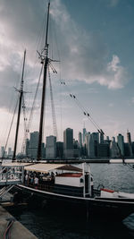 Sailboats moored at harbor in city against sky