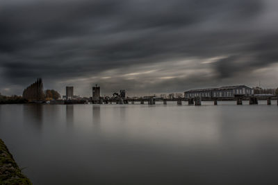 City at waterfront against cloudy sky