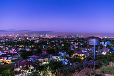 Aerial view of illuminated cityscape against blue sky at dusk