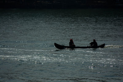 Silhouette people on boat in sea