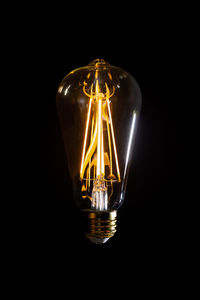 Close-up of illuminated light bulb on black background