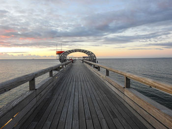 Pier over sea against sky during sunset