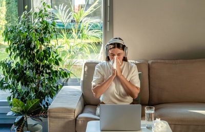 Sad crying woman having online psychotherapy session with professional psychotherapist on sofa 