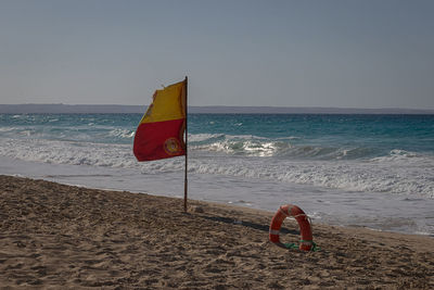 Red umbrella on beach against clear sky
