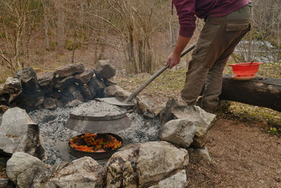 Low section of man with shovel preparing food on bonfire