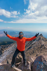 Portrait of man standing on rock against sky