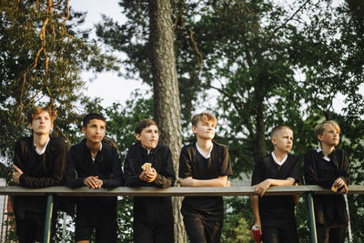 Low angle view of sports team leaning on railing while watching match