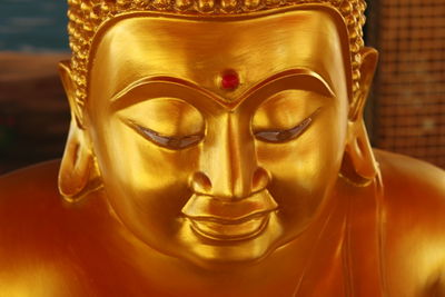The face of golden color buddha statue with blur background