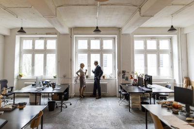 Businessman and businesswoman talking at the window in office