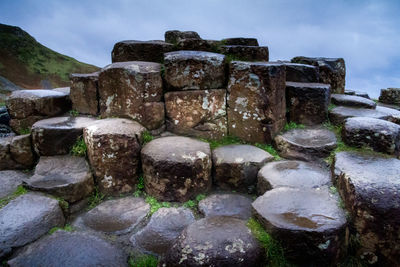 Stone wall by rocks against sky