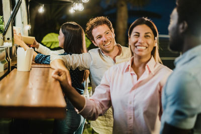 Smiling friends discussing at food truck counter