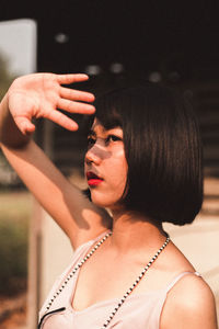 Young woman with short hair shielding eyes while standing outdoors