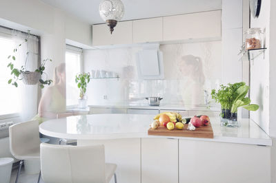 Digital composite image of ghost woman in kitchen at home