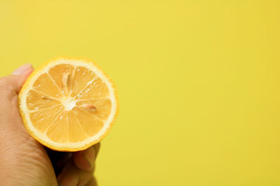 Close-up of hand holding apple against orange background