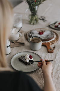 Woman eating chocolate cake with cream and raspberries