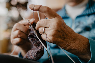 Midsection of woman knitting crochet at home