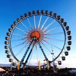 Low angle view of ferris wheel against clear blue sky